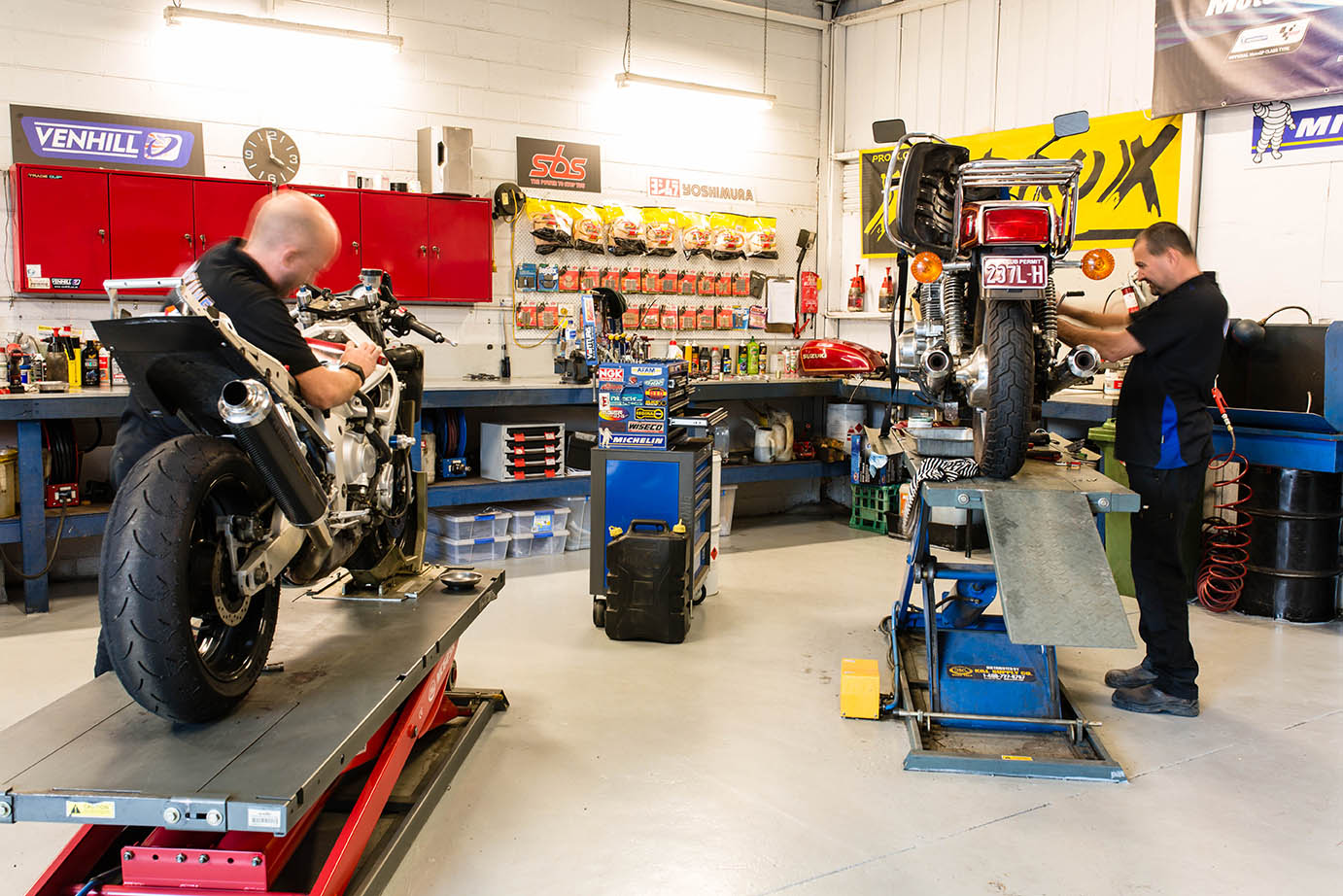 Mechanics assessing a motorbike for a roadworthy certificate
